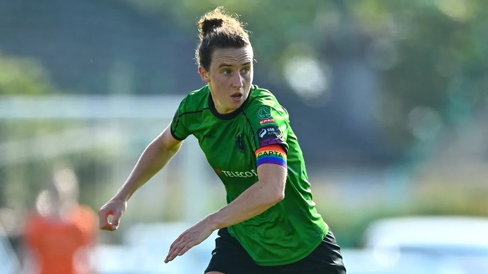 Female soccer player in green kit with captain's armband