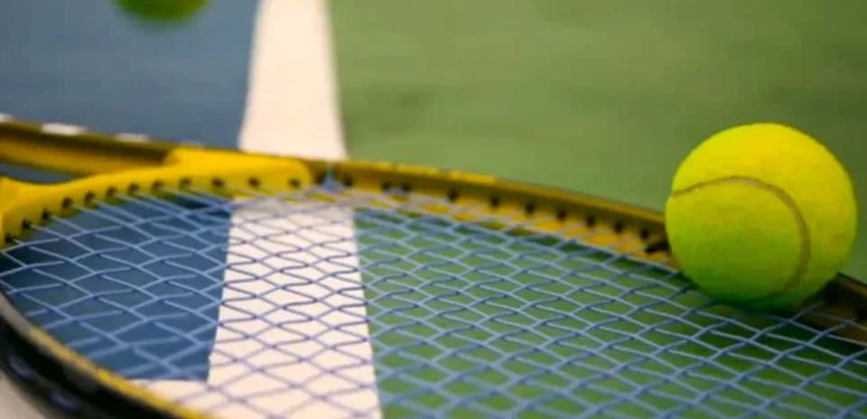 Tennis ball resting on a racket's strings