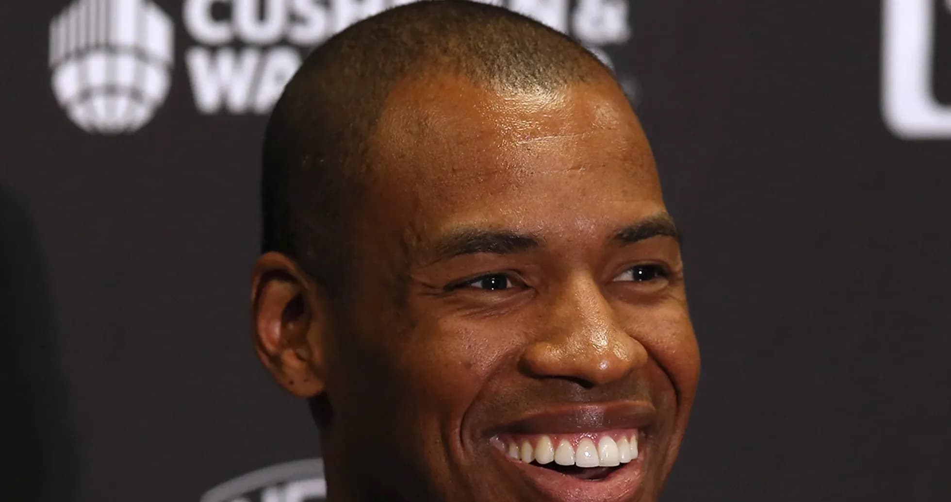 Man smiling at a press conference backdrop