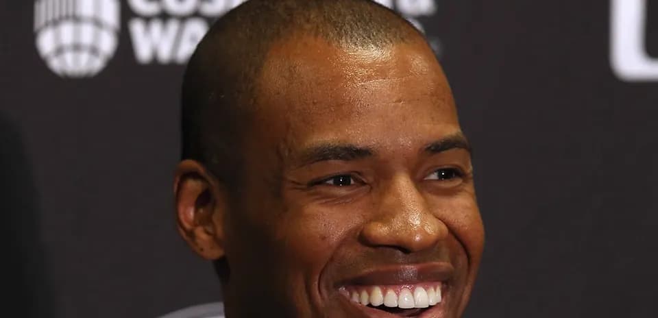 Man smiling at a press conference backdrop