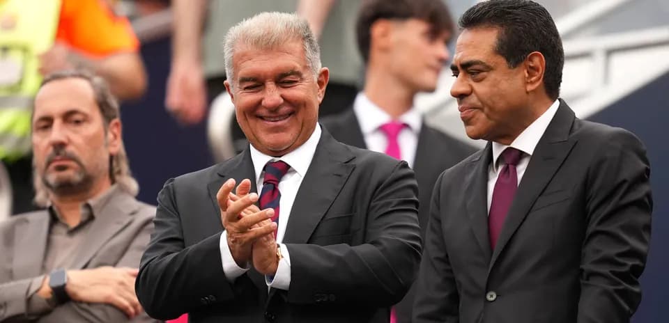 Two men in suits smiling and applauding at event
