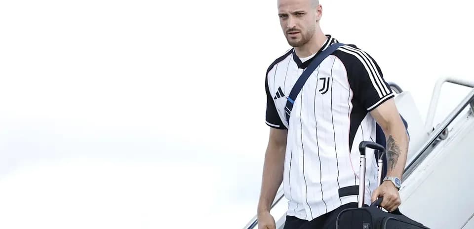 Player arriving with suitcase wearing Juventus jersey