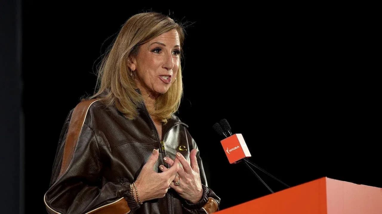 Woman speaking at a podium with WNBA logo