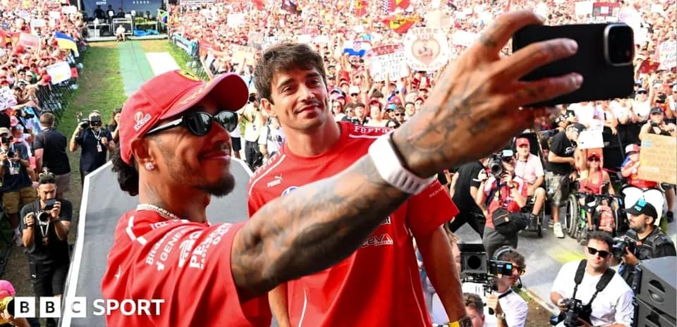 Two drivers taking a selfie with fans behind