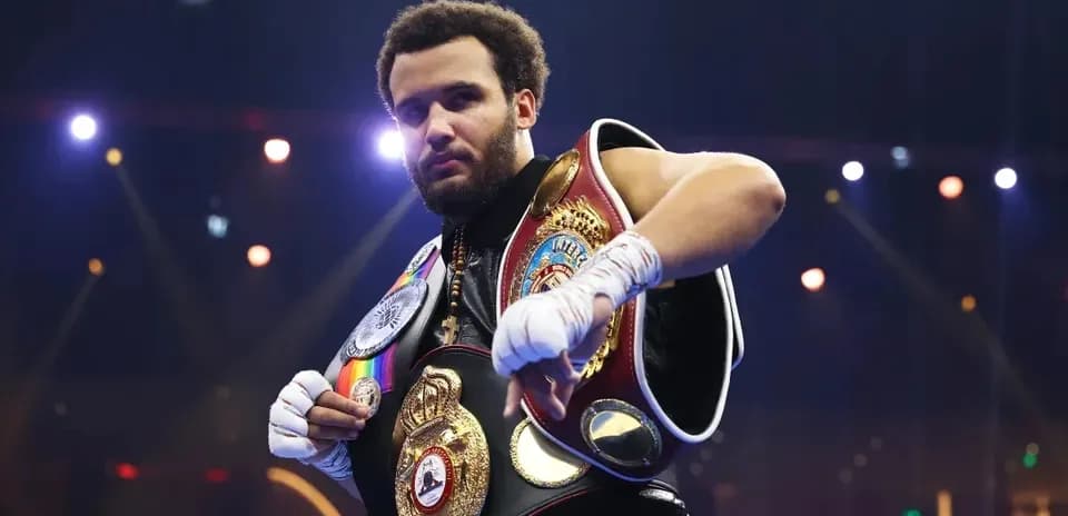 Boxer displaying championship belts in the ring