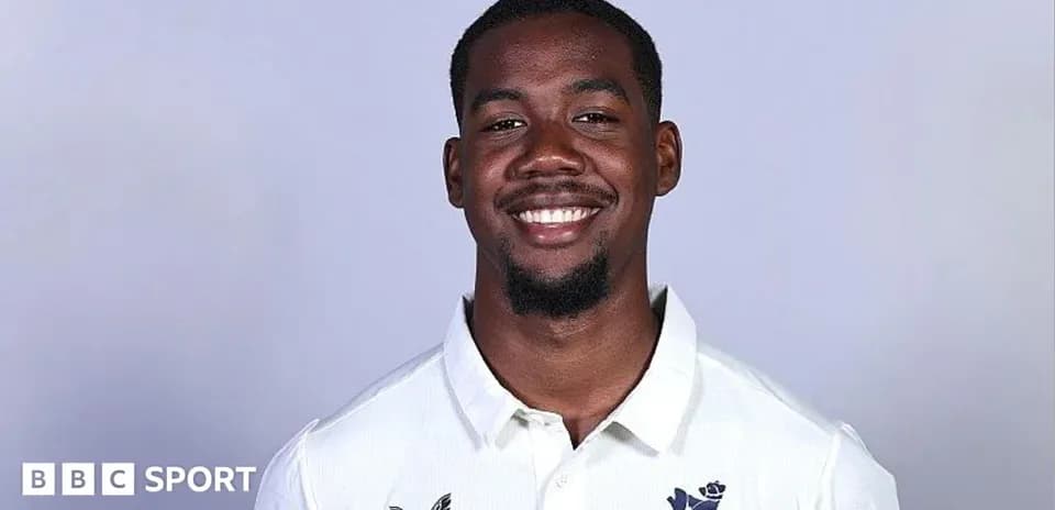 Smiling cricket player in white team jersey