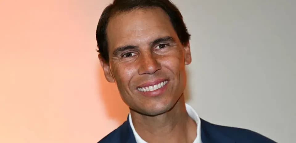 Man in suit smiling at event backdrop