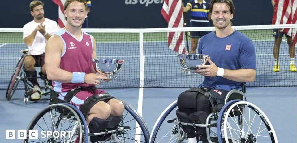 Two wheelchair tennis players holding trophies on court