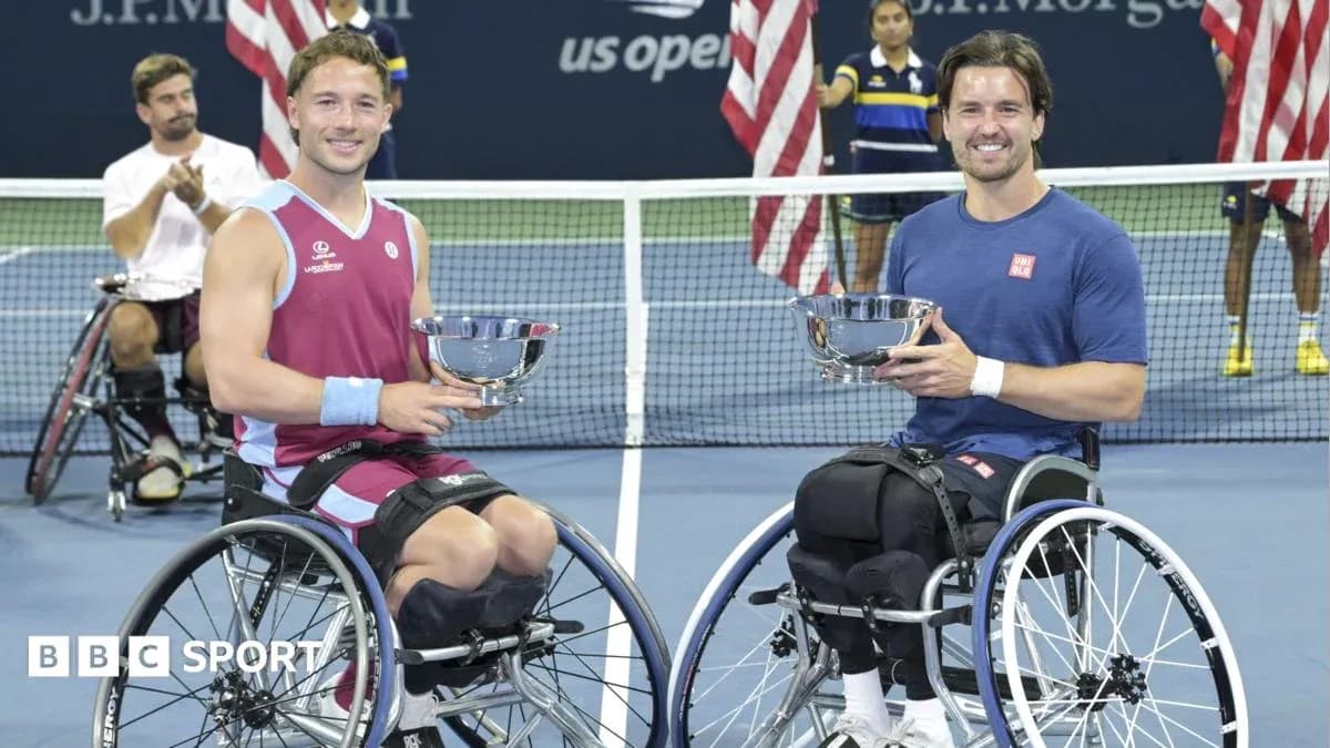 Two wheelchair tennis players holding trophies on court