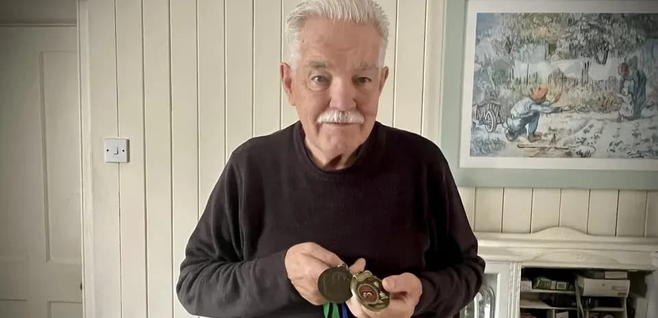 Older man holding medals in living room
