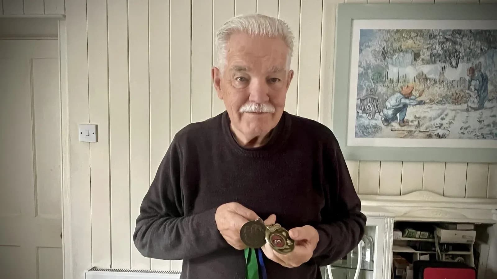 Older man holding medals in living room