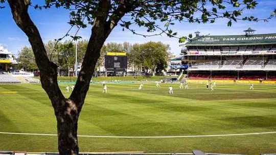 Cricket match in progress at stadium with spectators