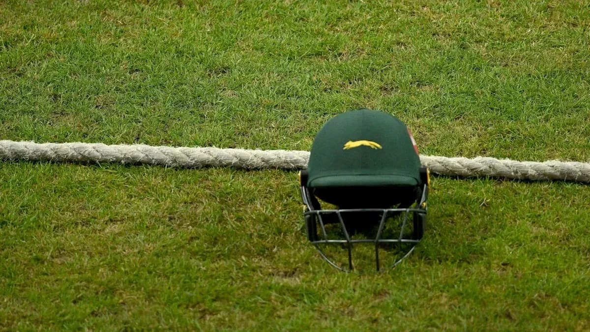Cricket helmet resting on grass near boundary rope