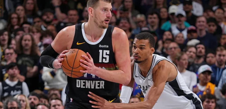 Nikola Jokić dribbling while being closely guarded