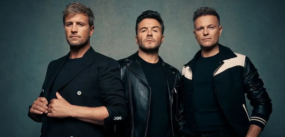 Three men posing together in stylish outfits
