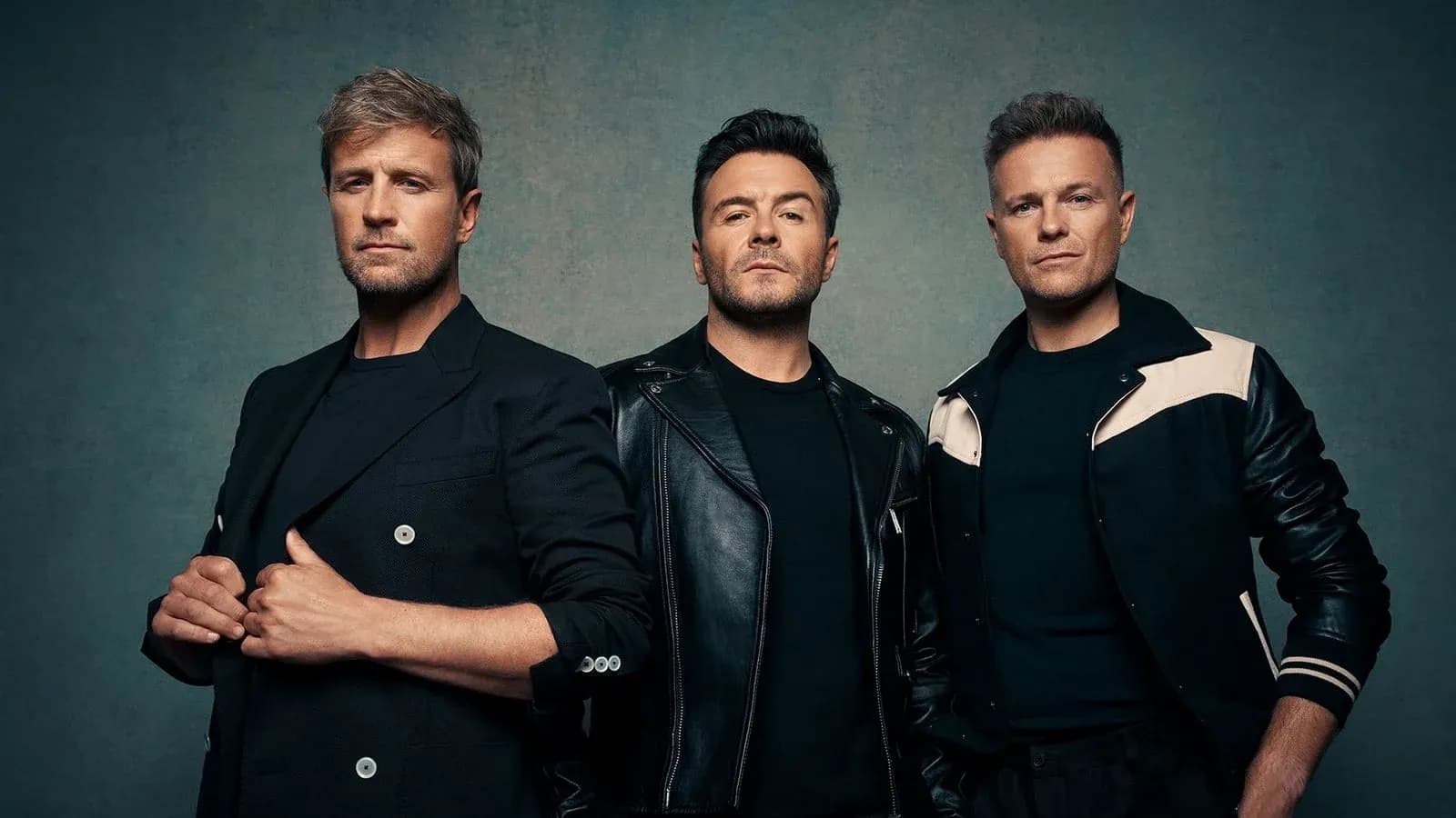 Three men posing together in stylish outfits