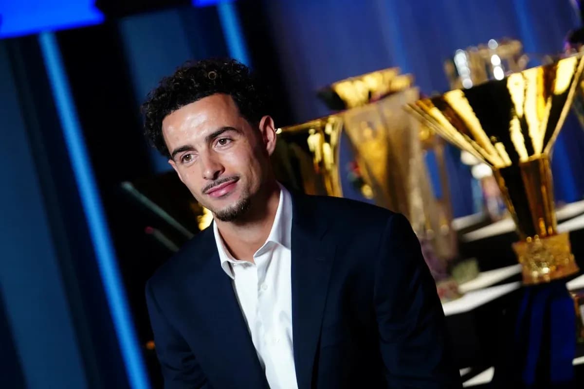 Man in suit posing with trophies in background