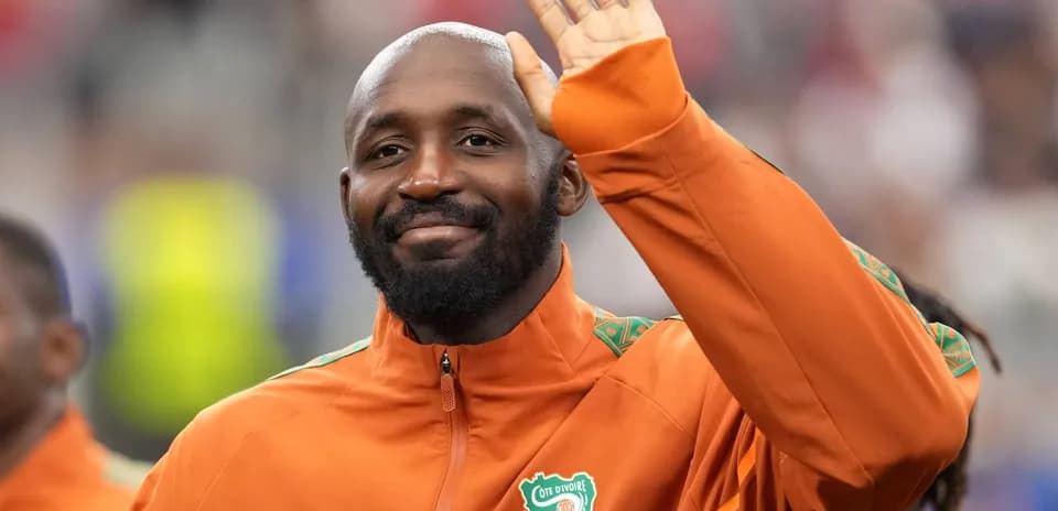 Player waving during pre-match ceremony in orange jacket