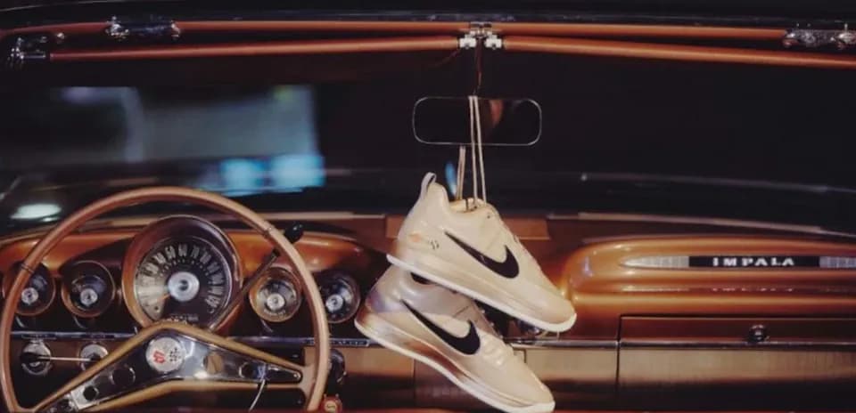 Nike sneakers hanging from classic car dashboard