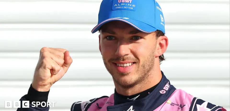 Driver celebrating with raised fist in Alpine outfit