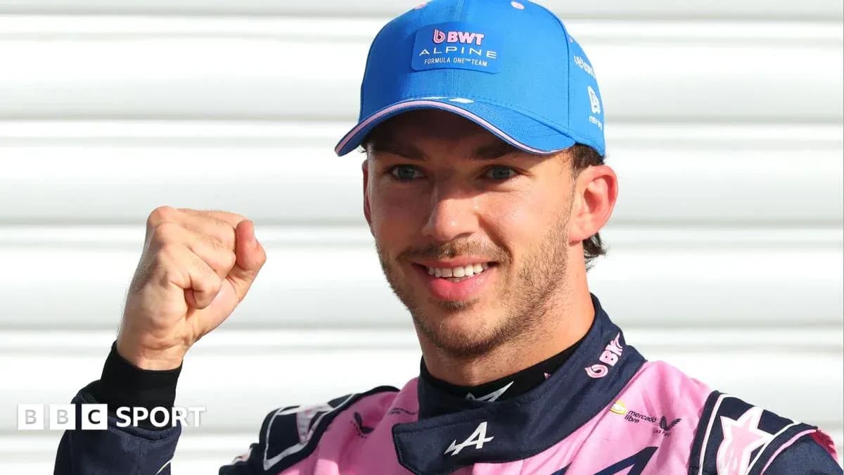 Driver celebrating with raised fist in Alpine outfit