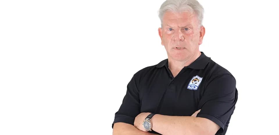 Coach with arms crossed, wearing black polo shirt