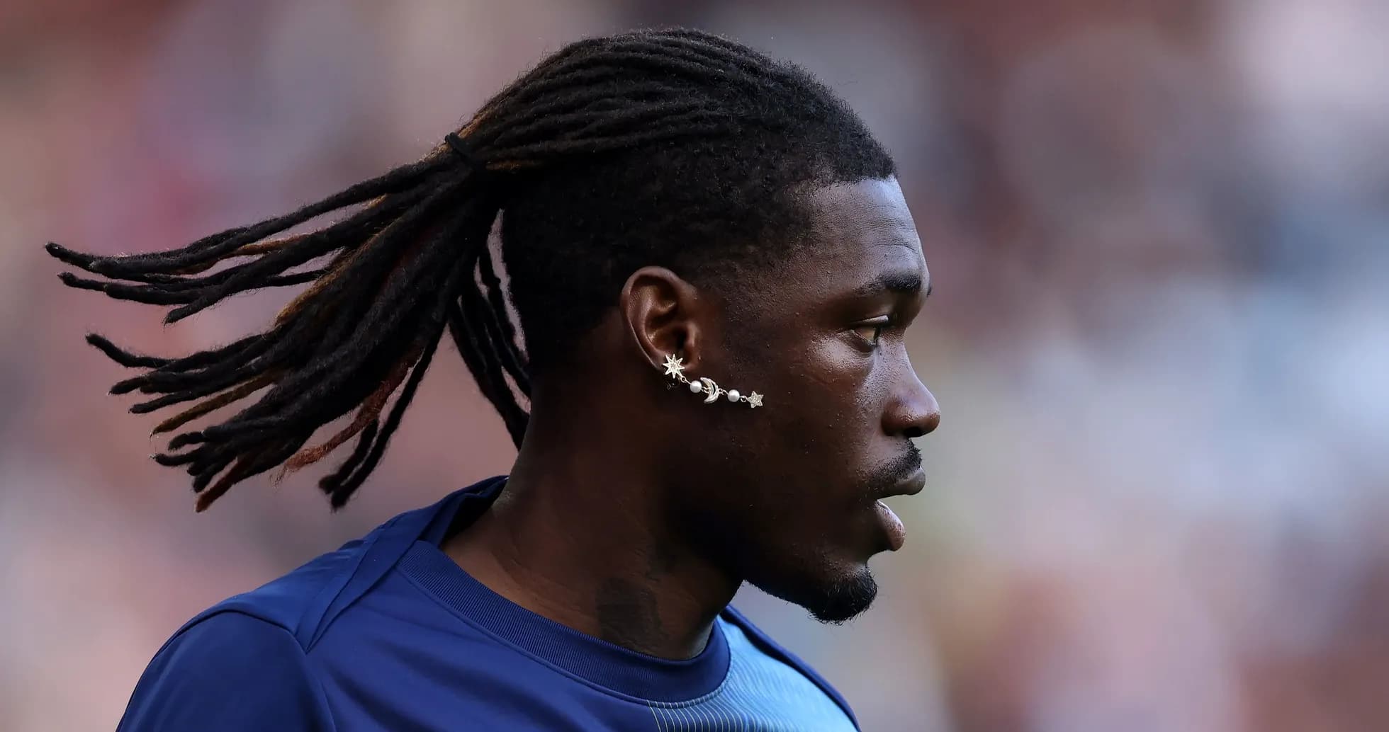Player with long hair and earrings during warm-up