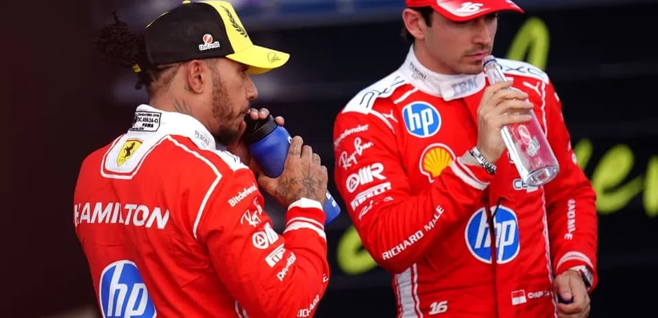 Two drivers in red racing suits drinking water