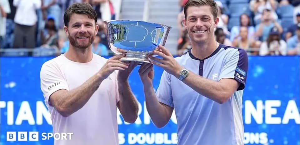 Two tennis players holding a trophy on court
