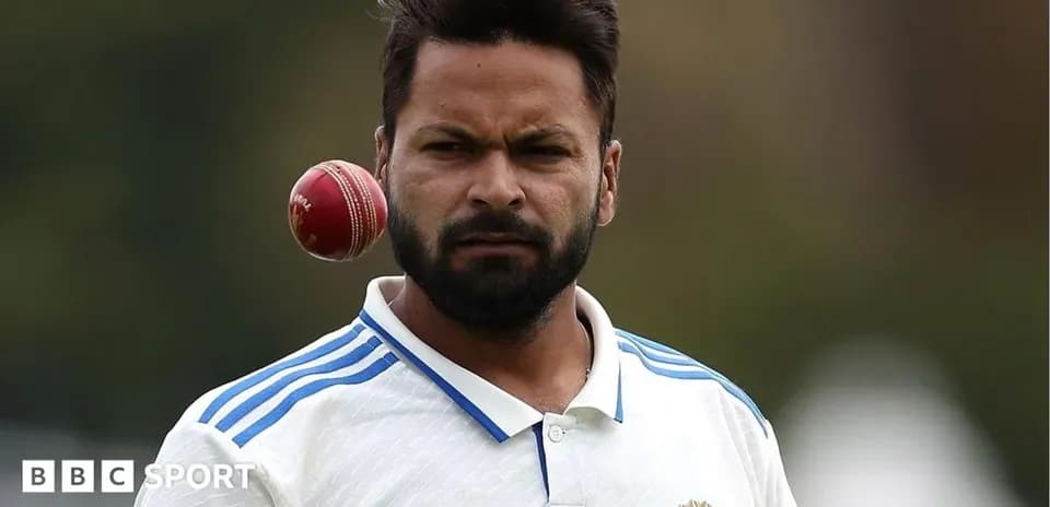 Cricketer preparing to bowl with a red ball