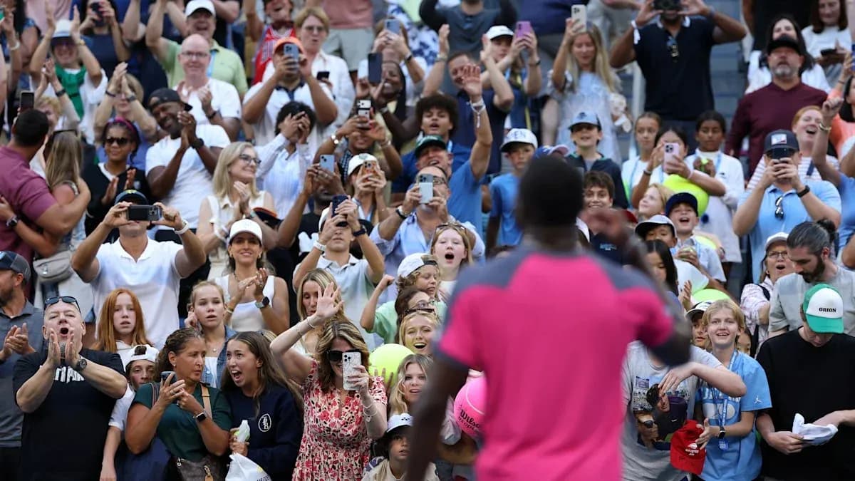 Crowd cheering and taking photos at tennis event