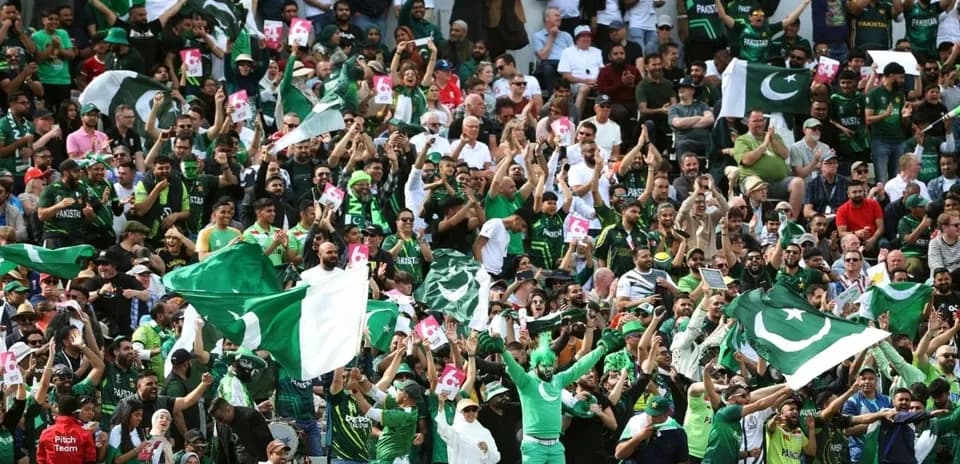 Crowd of fans cheering with Pakistan flags in stadium