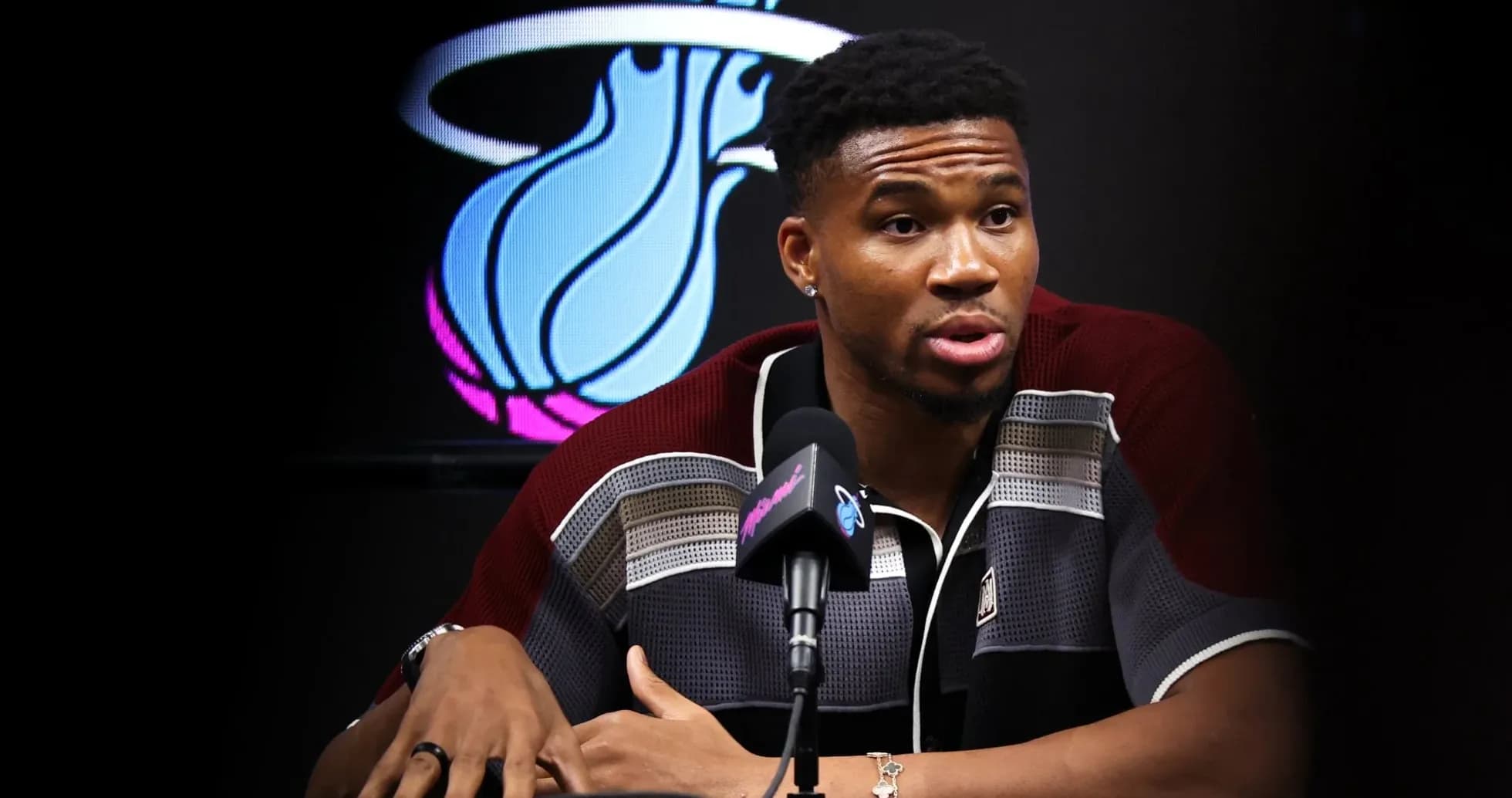 Player speaking at press conference with team logo backdrop