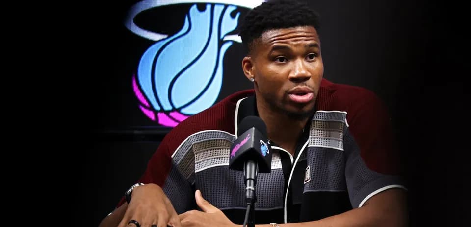 Player speaking at press conference with team logo backdrop