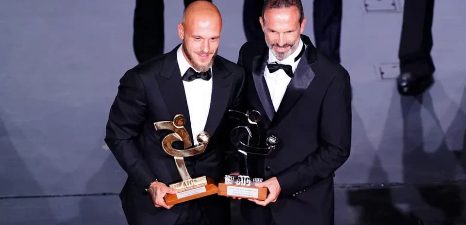 Two award winners holding trophies on stage