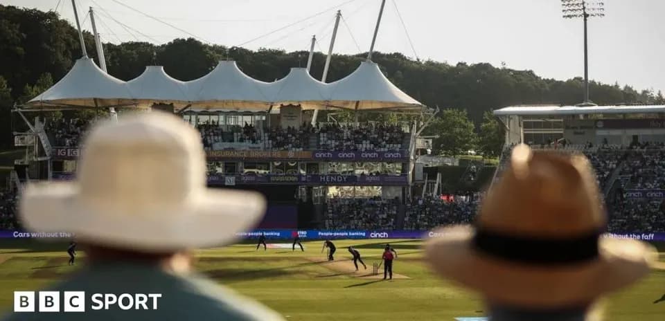 Cricket match at stadium with spectators in foreground
