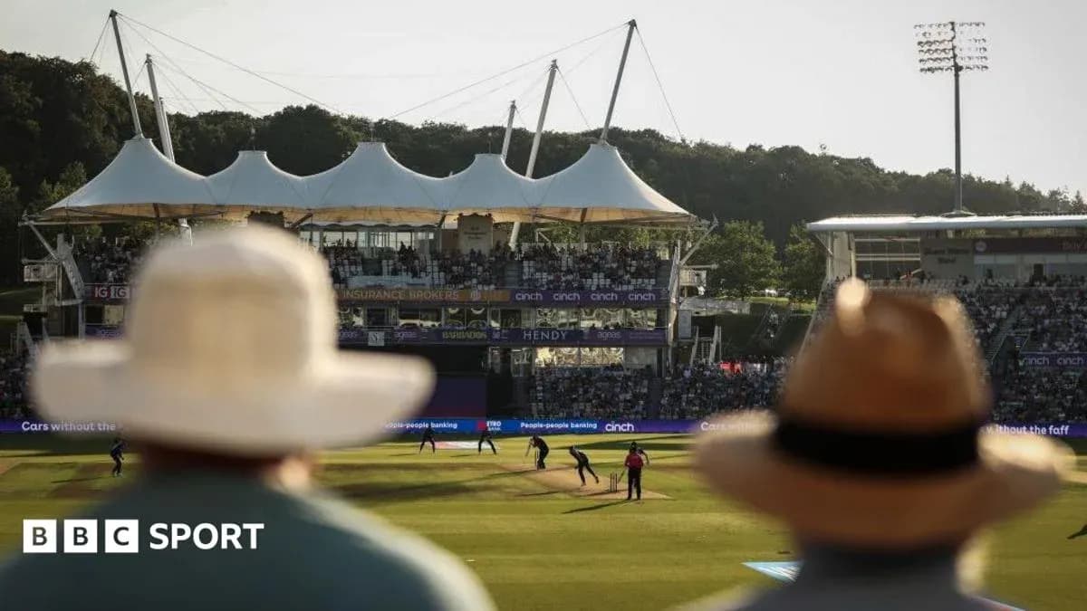Cricket match at stadium with spectators in foreground