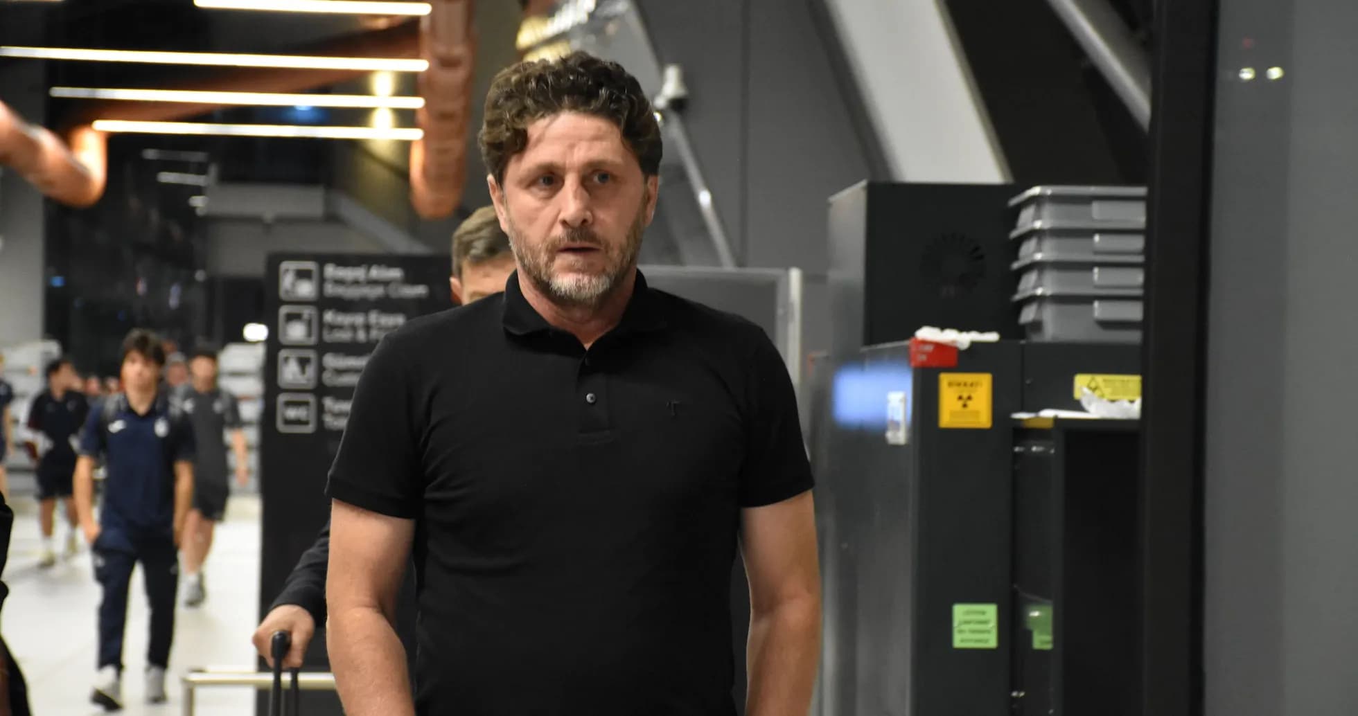 Coach walking through airport terminal with team members