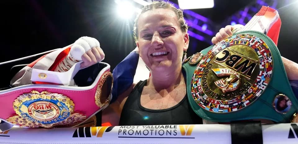 Female boxer celebrating with championship belts
