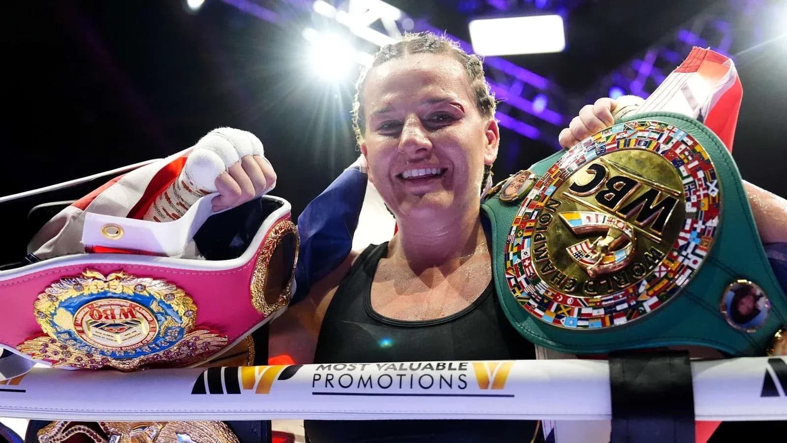 Female boxer celebrating with championship belts