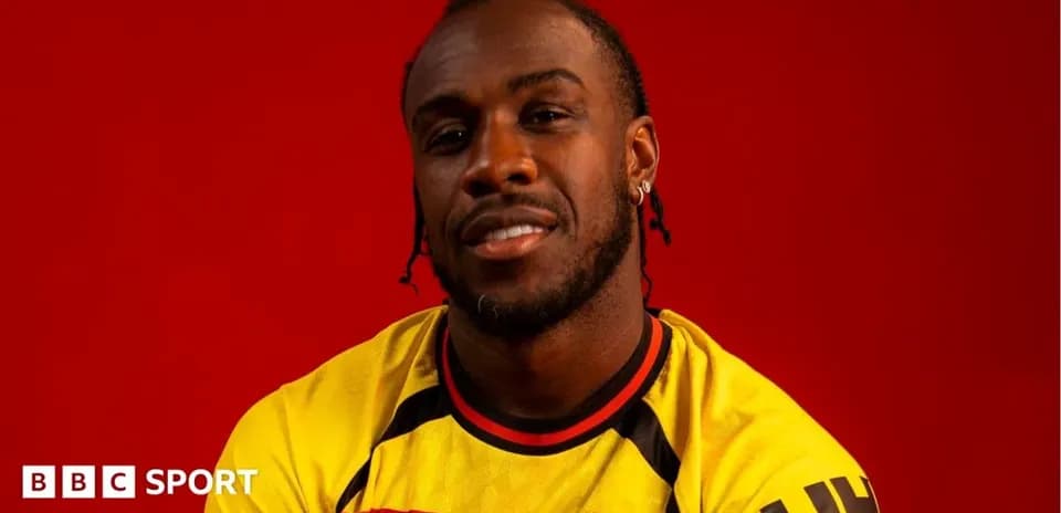 Player posing in Watford FC jersey against red background