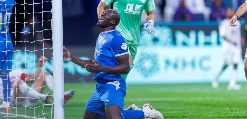 Player kneeling near goal post after missed opportunity