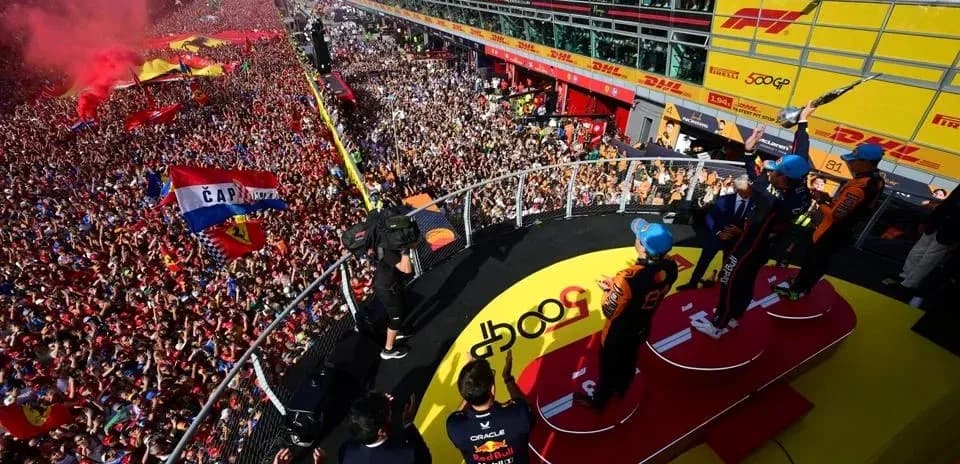 Drivers celebrating on podium with crowd in background