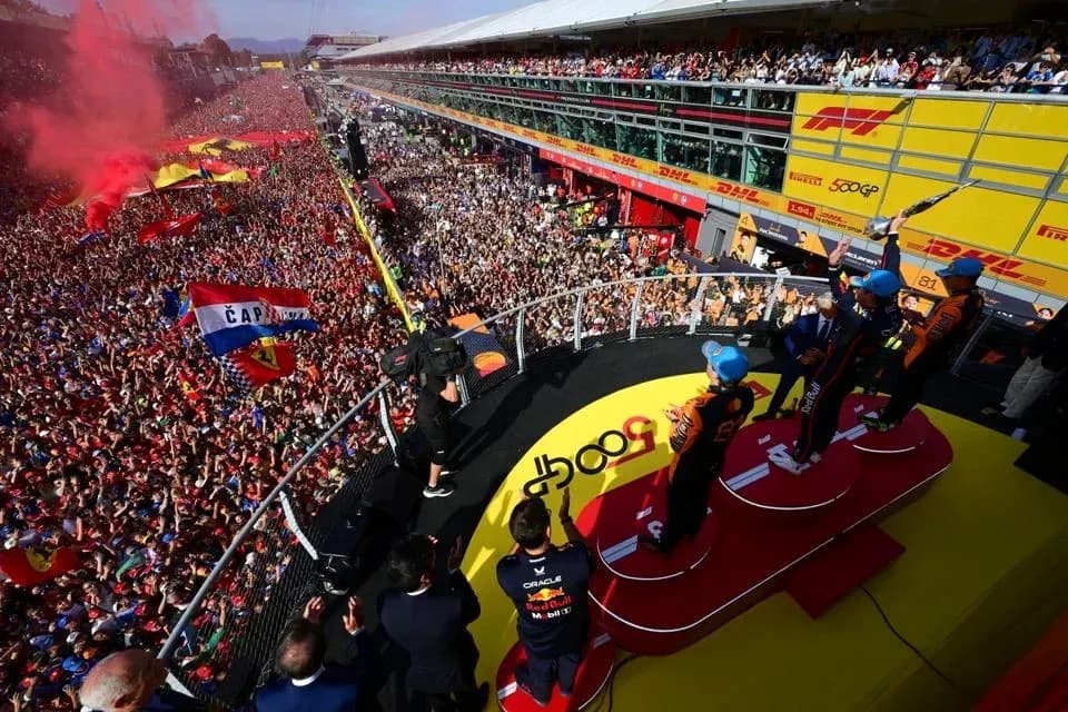 Drivers celebrating on podium with crowd in background