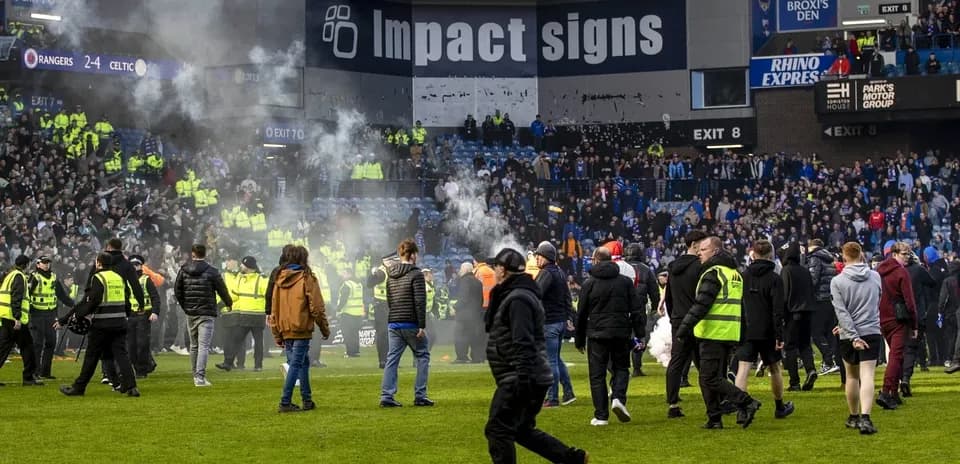 Crowd on pitch with smoke after football match