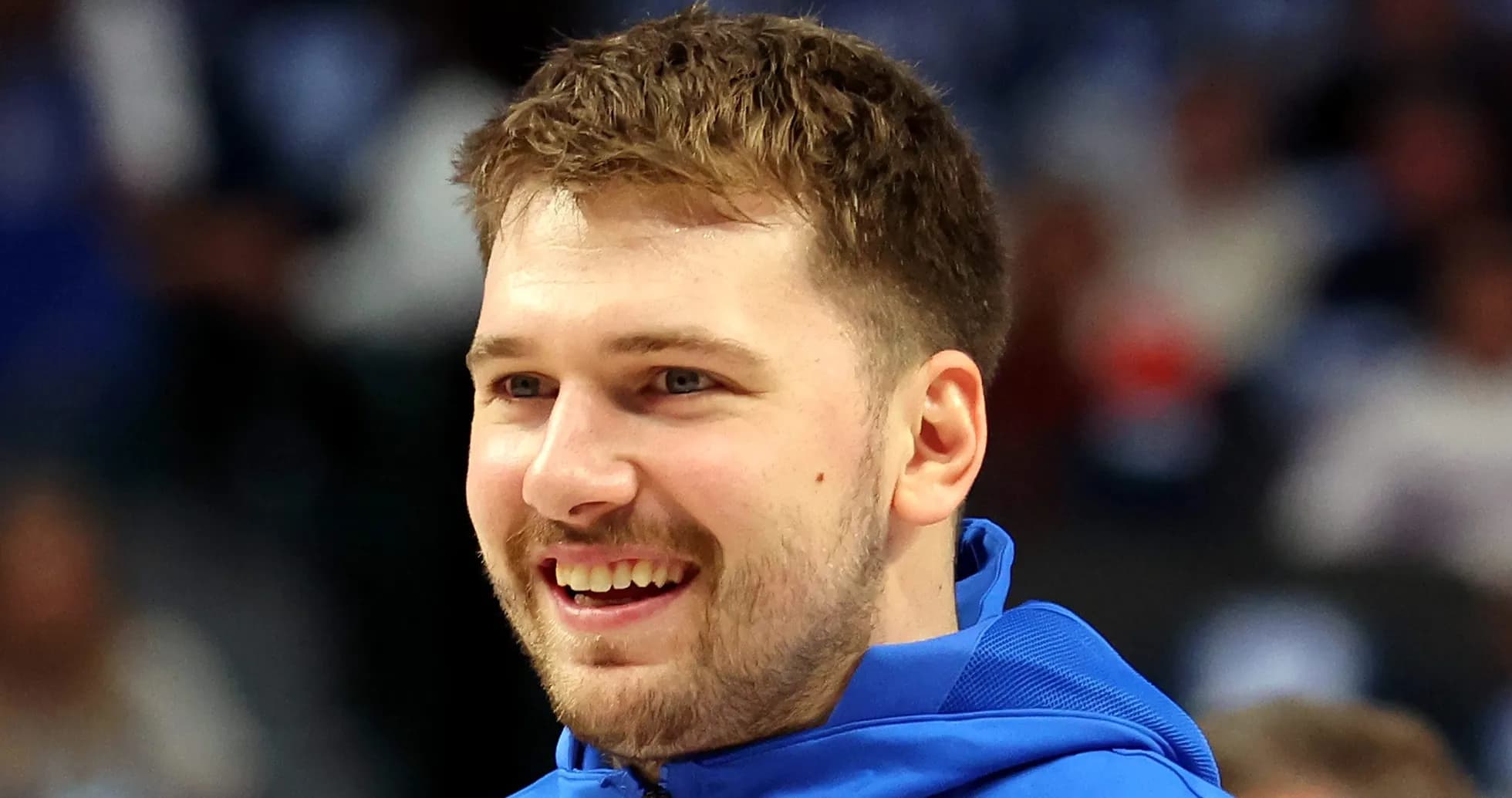 Player smiling while wearing blue warm-up jacket