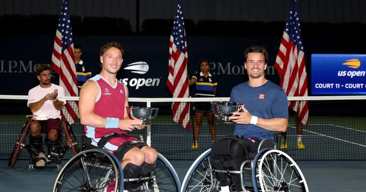 Two wheelchair tennis players holding trophies on court