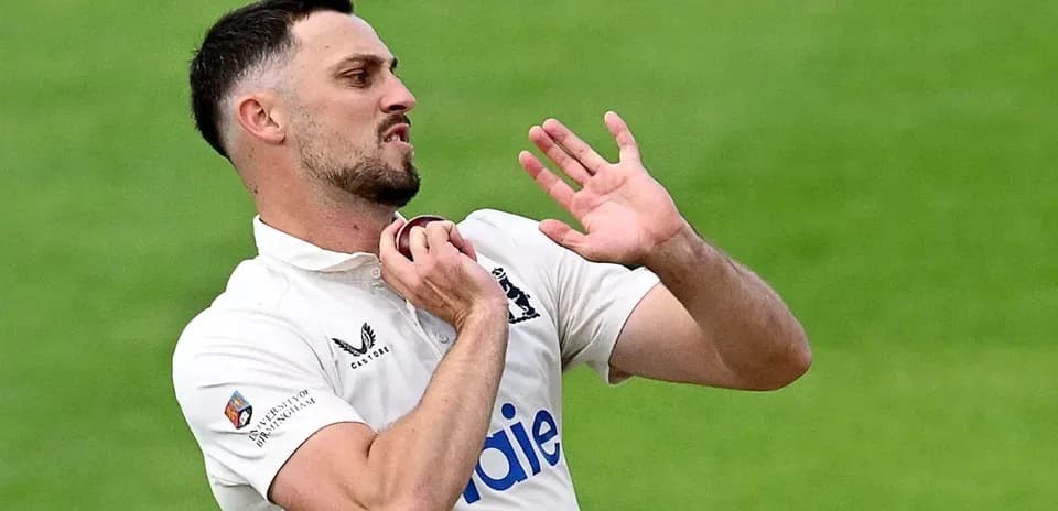 Cricketer adjusting collar during match play