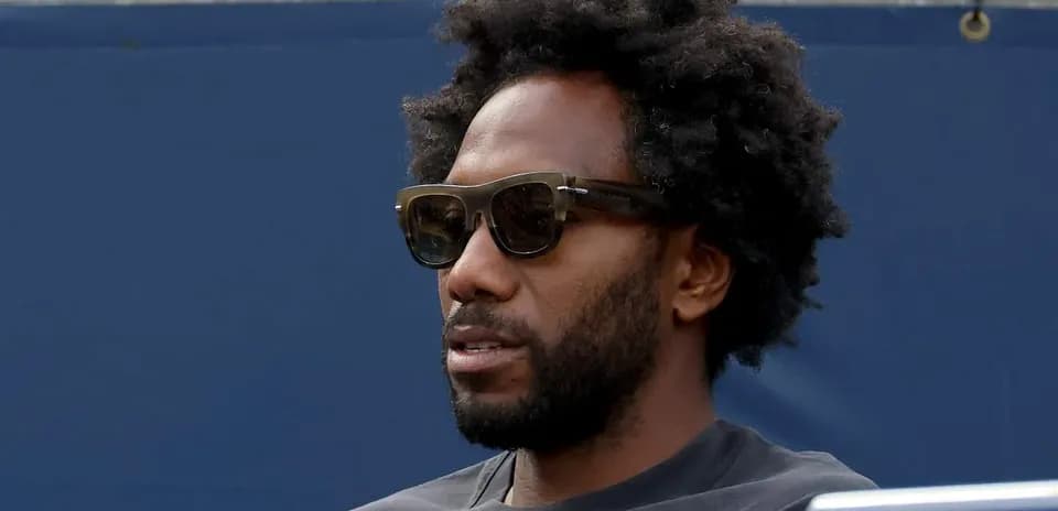 Man wearing sunglasses seated at event
