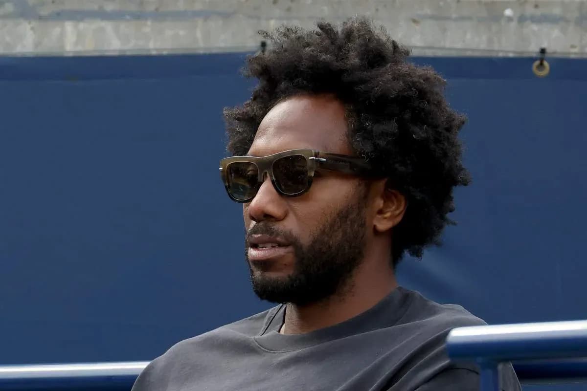Man wearing sunglasses seated at event